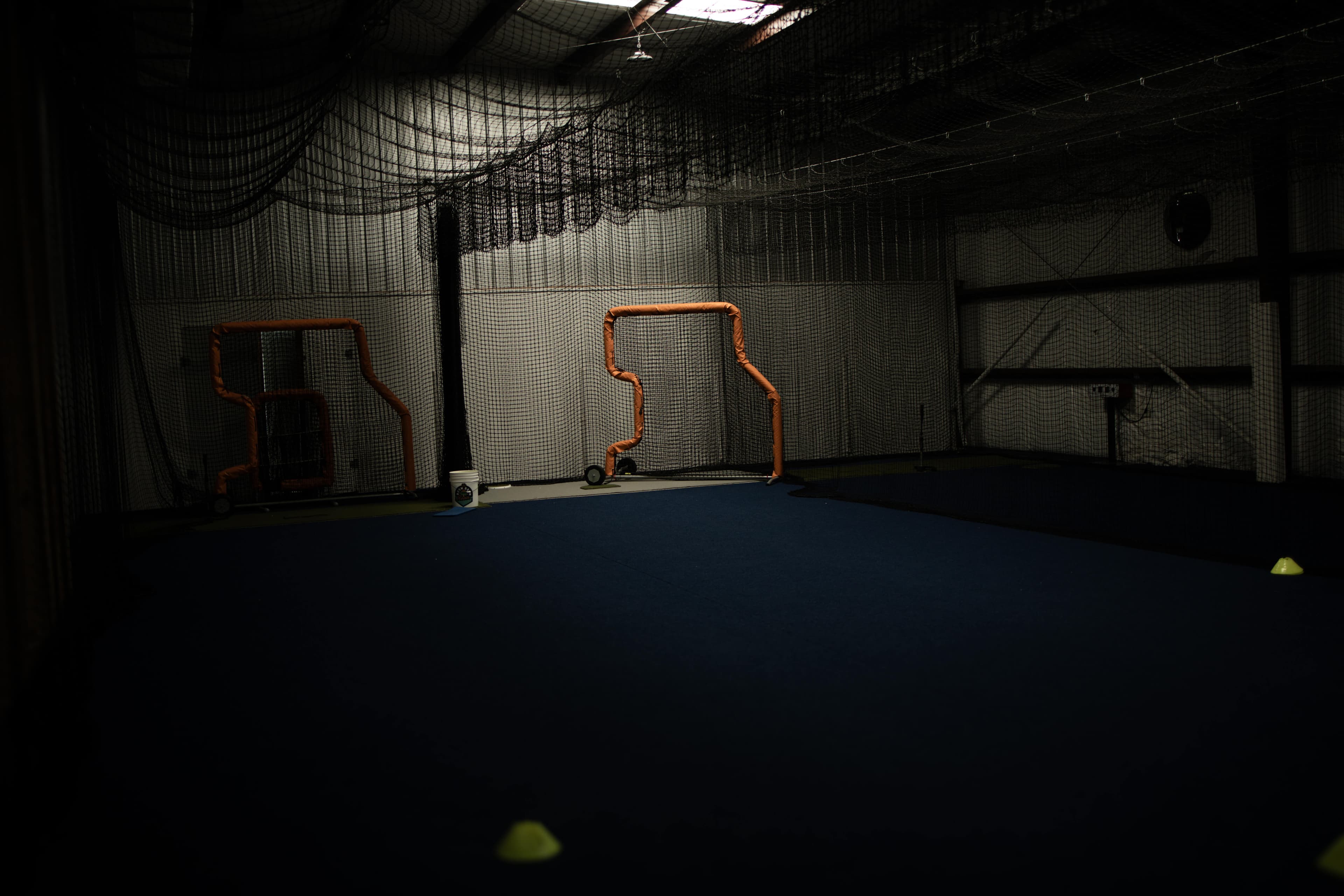 Hitter taking a swing in a HitTrax-equipped batting cage that tracks exit velocity and launch angle
